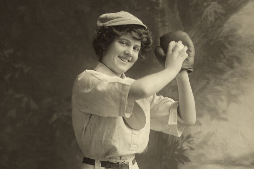 Black and white image of woman posing in baseball uniform