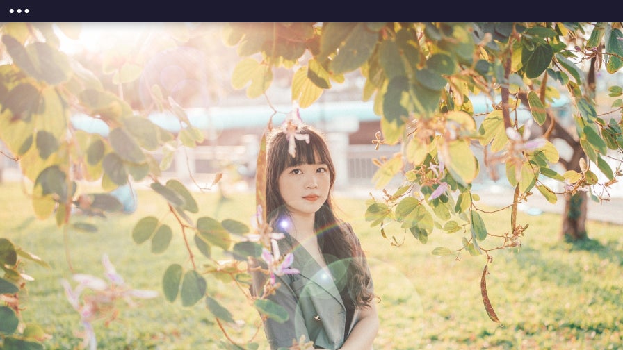 lens flare effect on photo of woman framed by tree leaves