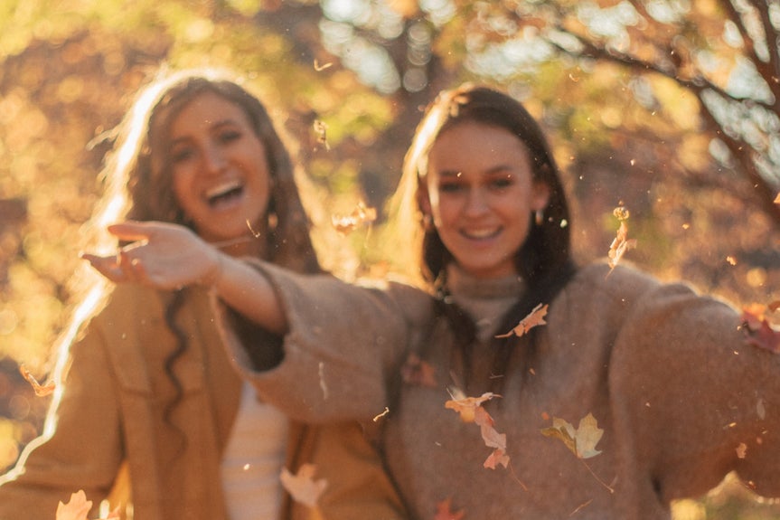 blurred image of friends posing with falling leaves