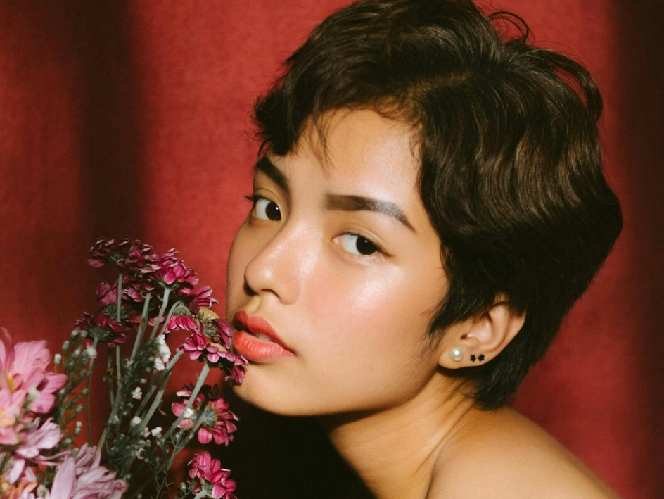 Close up portrait of woman with flowers and velvet curtain background